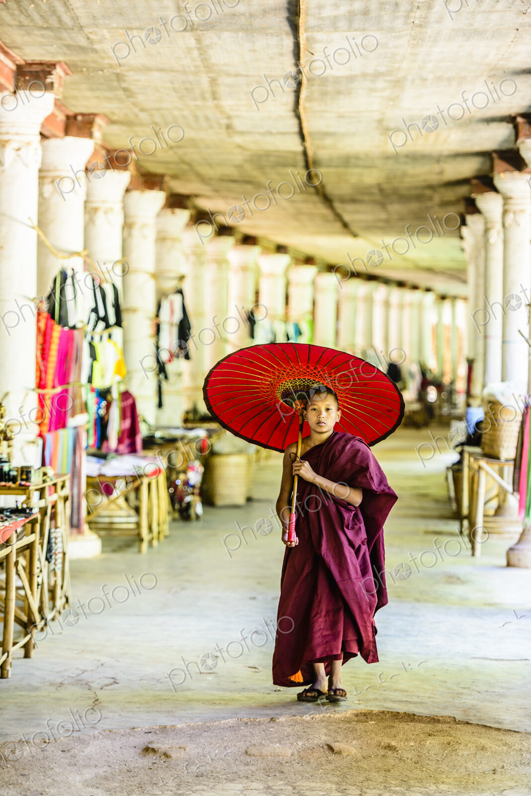 Asian monk-in-training with parasol walking in hallway