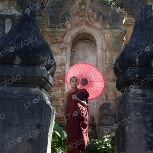 Asian monk-in-training with parasol walking on Buddhist shrine Asian monk-in-training with parasol walking on Buddhist shrine