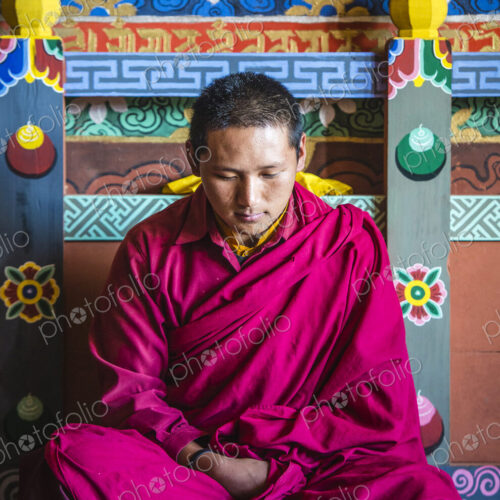 Asian monk reading on temple floor