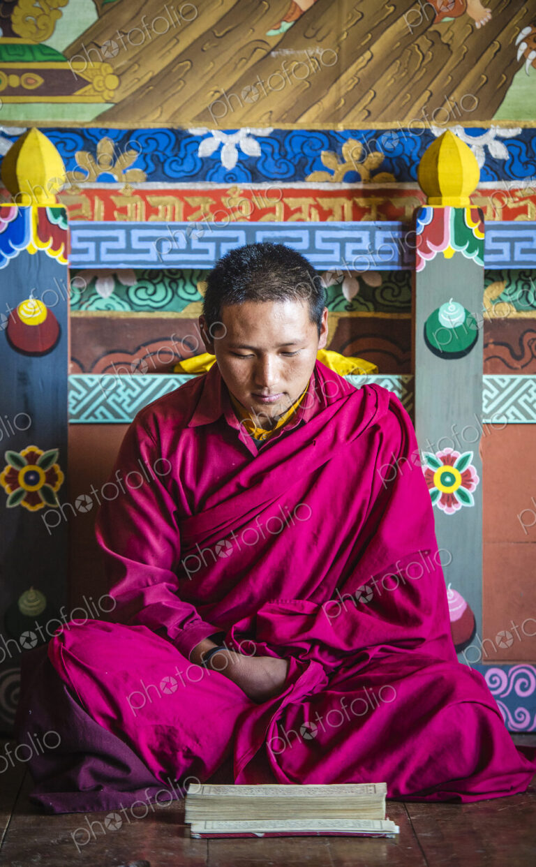 Asian monk reading on temple floor