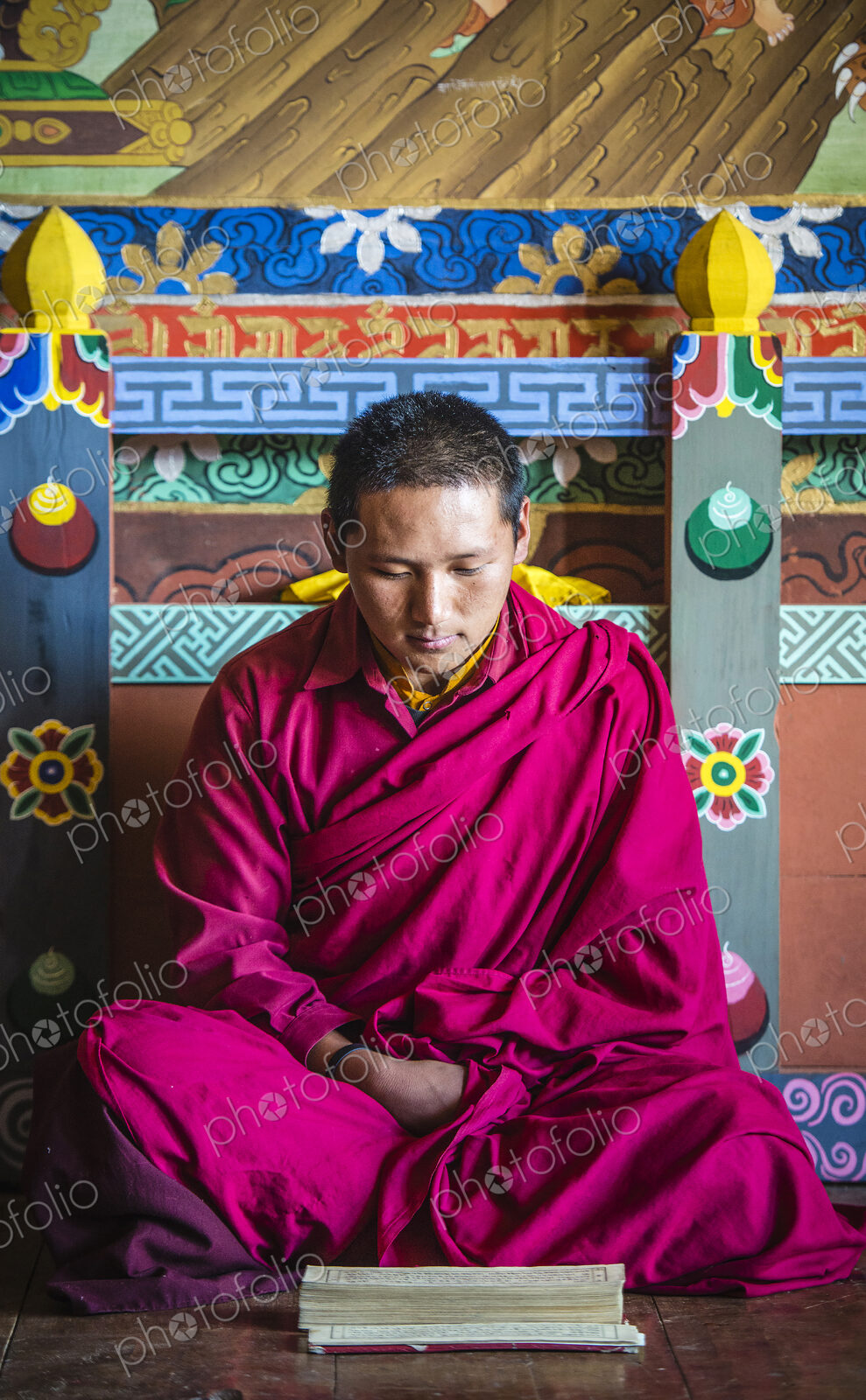 Asian monk reading on temple floor