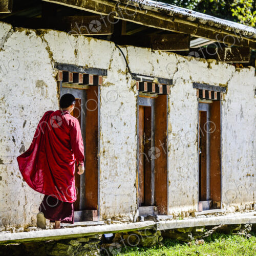 Asian monk walking by monastery doors Asian monk walking by monastery doors