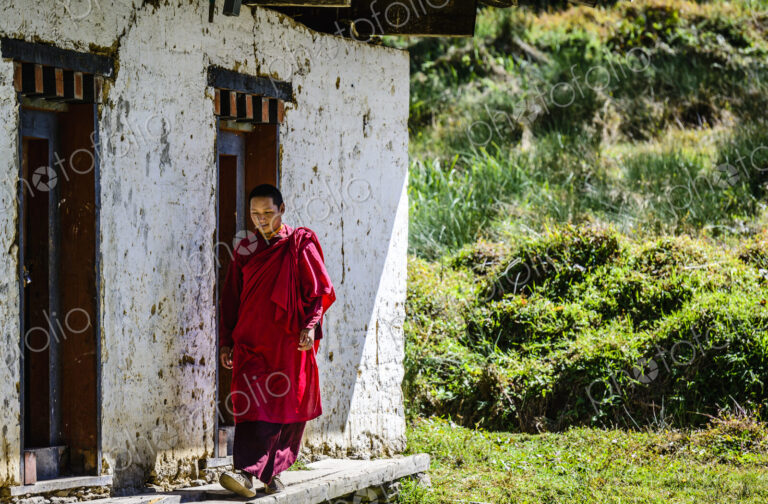 Asian monk walking by monastery doors