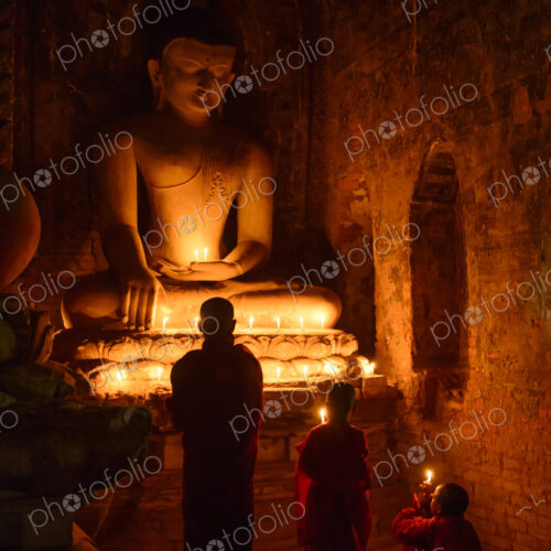 Asian monks-in-training lighting candles at Buddha shrine Asian monks-in-training lighting candles at Buddha shrine