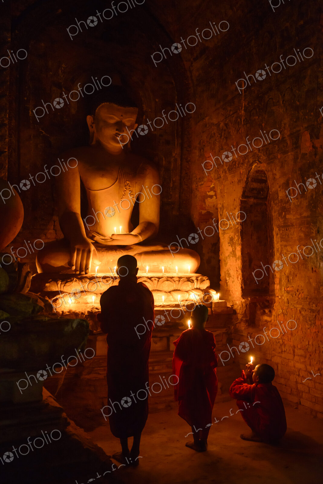 Asian monks-in-training lighting candles at Buddha shrine