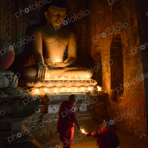 Asian monks-in-training lighting candles at Buddha shrine Asian monks-in-training lighting candles at Buddha shrine