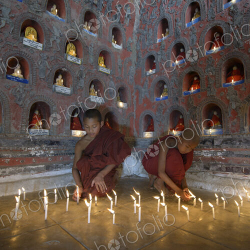Asian monks-in-training lighting candles in ancient temple Asian monks-in-training lighting candles in ancient temple