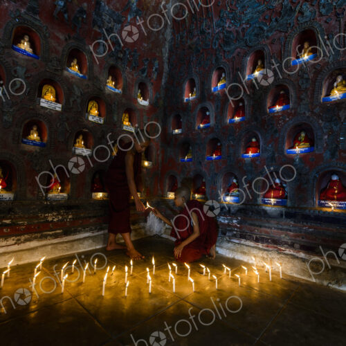 Asian monks-in-training lighting candles in ancient temple Asian monks-in-training lighting candles in ancient temple