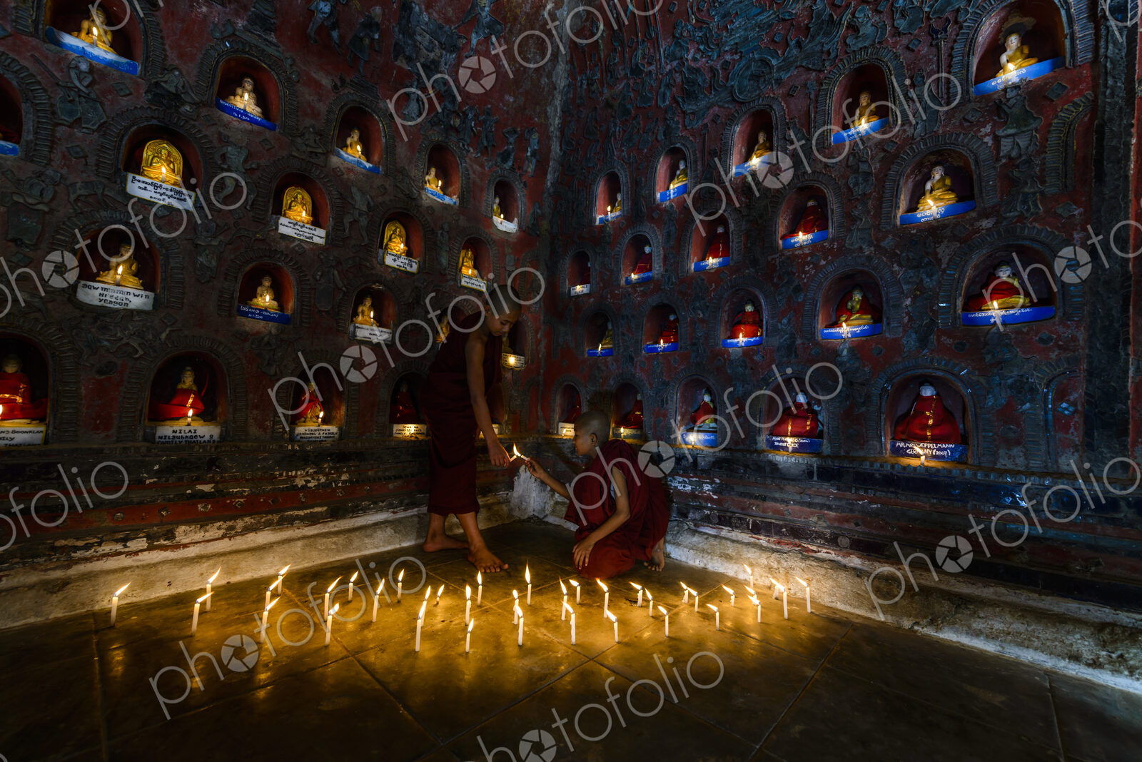 Asian monks-in-training lighting candles in ancient temple