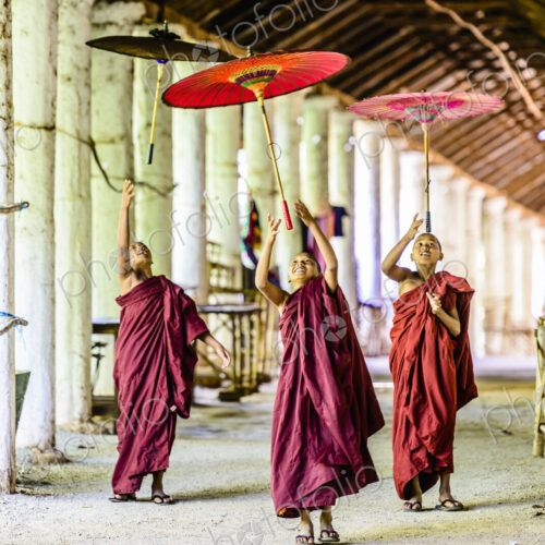 Asian monks-in-training playing with parasols in hallway Asian monks-in-training playing with parasols in hallway