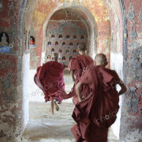 Asian monks-in-training running in dilapidated temple hallway Asian monks-in-training running in dilapidated temple hallway