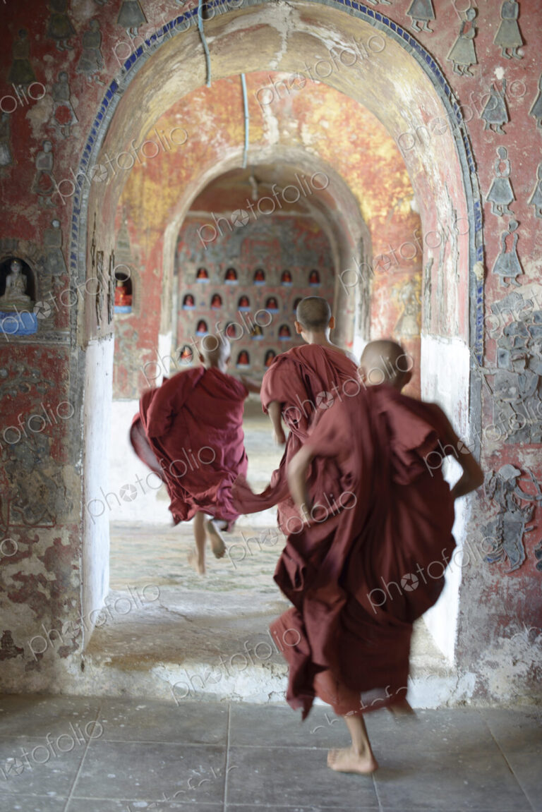 Asian monks-in-training running in dilapidated temple hallway