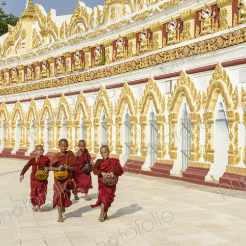 Asian monks-in-training running outside ornate temple Asian monks-in-training running outside ornate temple