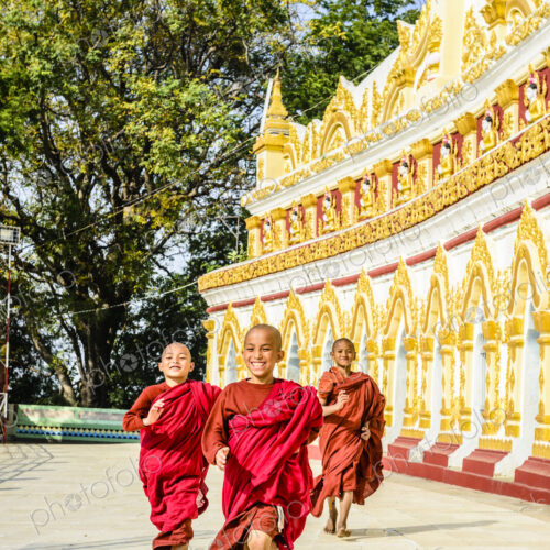 Asian monks-in-training running outside ornate temple Asian monks-in-training running outside ornate temple