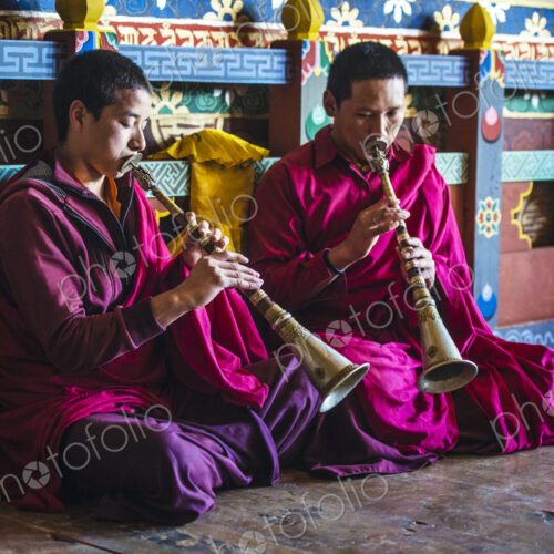 Asian monks playing instruments on temple floor