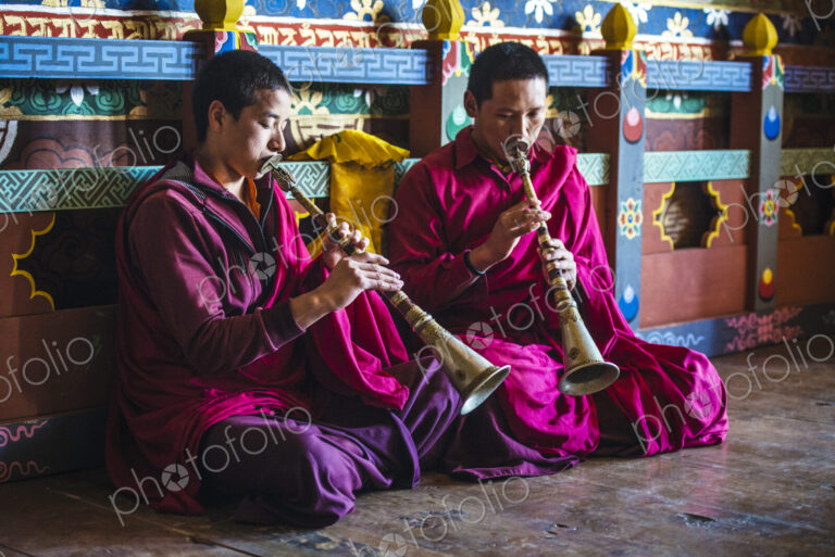 Asian monks playing instruments on temple floor