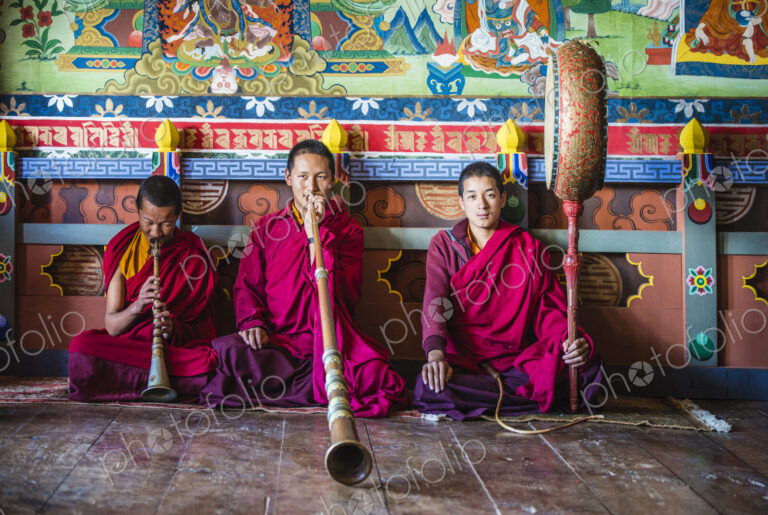 Asian monks playing instruments on temple floor