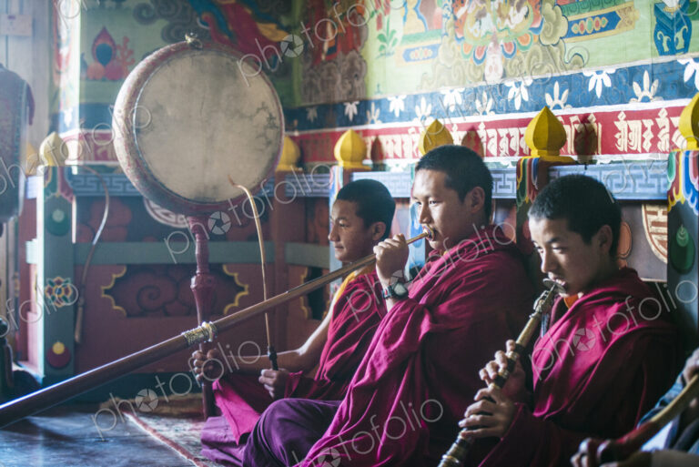 Asian monks playing instruments on temple floor