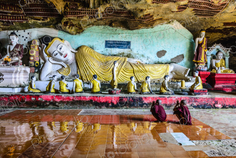 Asian monks praying to Buddha statue in temple