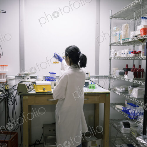 Asian scientist examining fluid in beaker