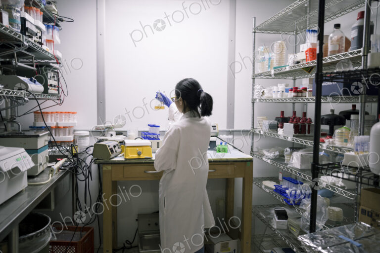 Asian scientist examining fluid in beaker