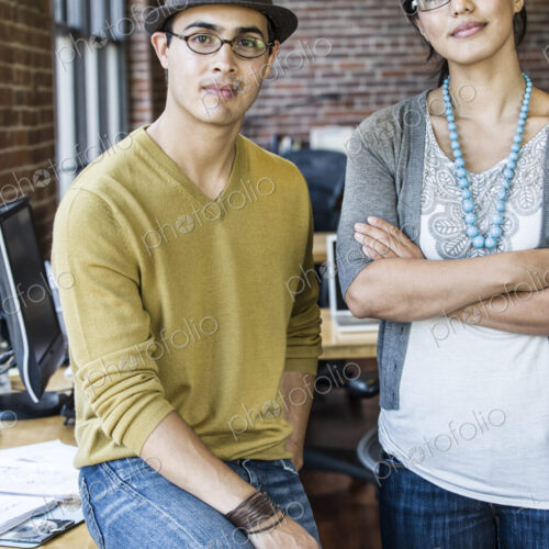 Asian woman and Hispanic man together at a creative office work station.