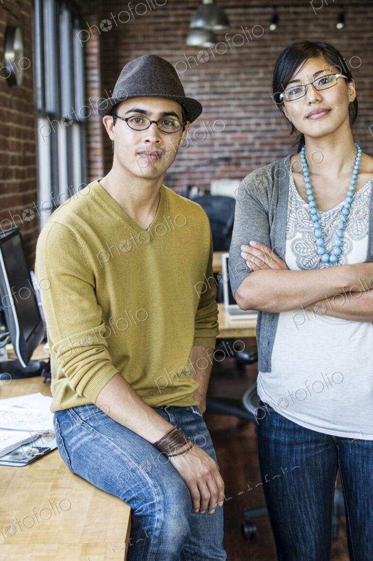 Asian woman and Hispanic man together at a creative office work station.