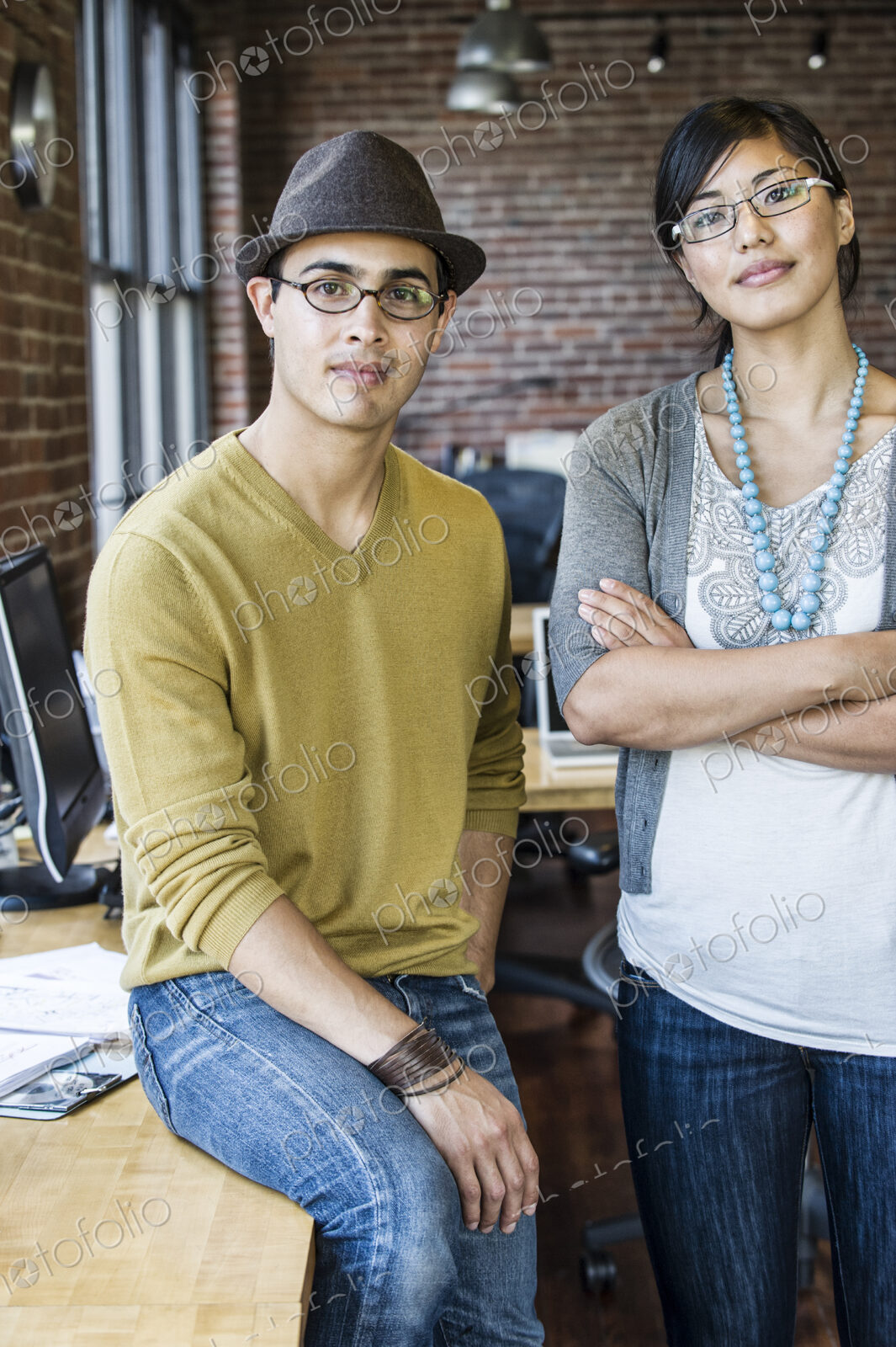 Asian woman and Hispanic man together at a creative office work station.