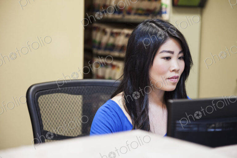 Asian woman and east indian woman working on a computer in a medical office.