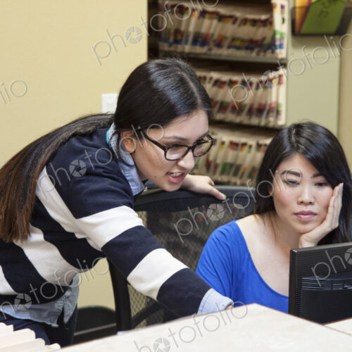 Asian woman and east indian woman working on a computer in a medical office. Asian woman and east indian woman working on a computer in a medical office.