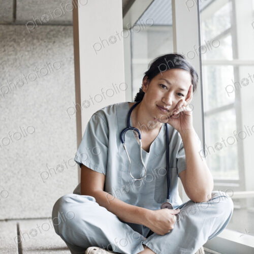 Asian woman doctor in scrubs in a hospital hallway. Asian woman doctor in scrubs in a hospital hallway.
