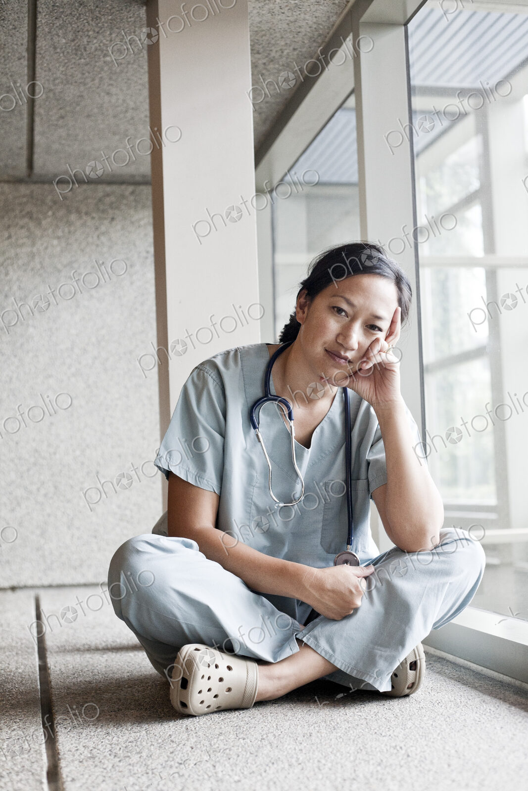 Asian woman doctor in scrubs in a hospital hallway.