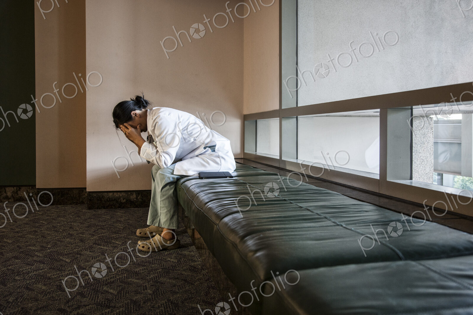 Asian woman doctor under stress sitting on a bench in a hospital.