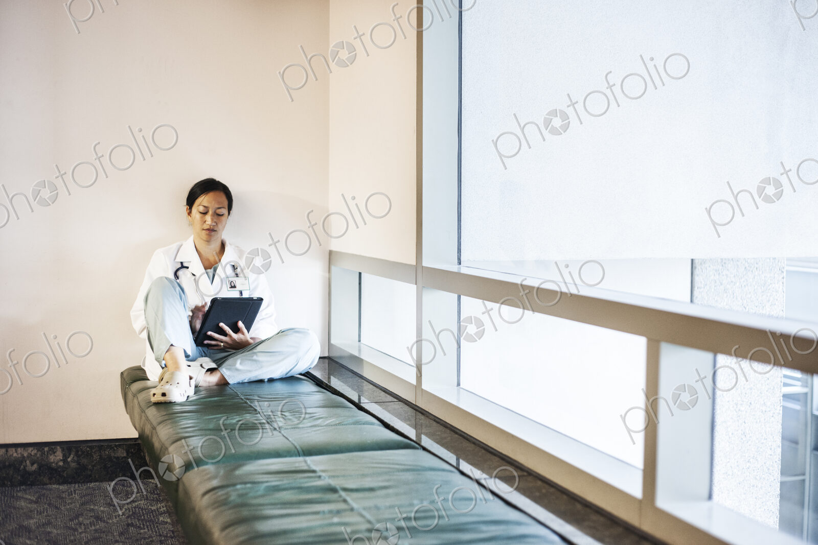 Asian woman doctor using a notebook computer and wearing a lab coat and stethescope.