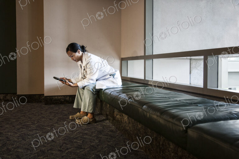 Asian woman doctor using a notebook computer and wearing a lab coat and stethescope.