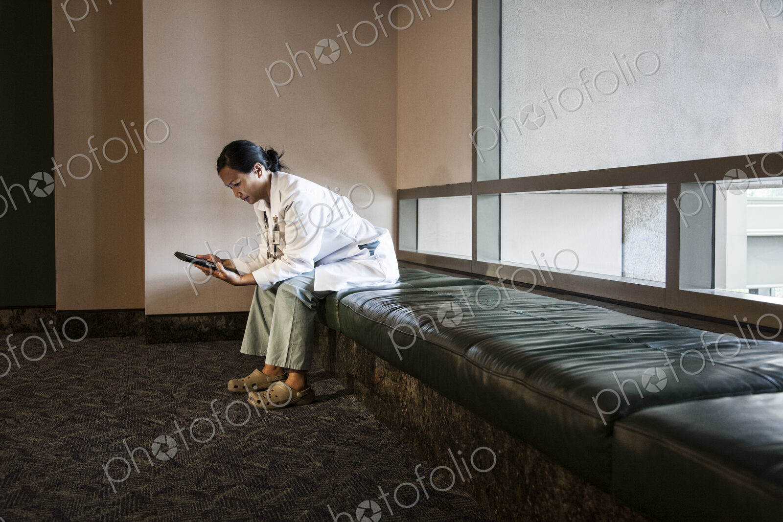 Asian woman doctor using a notebook computer and wearing a lab coat and stethescope.