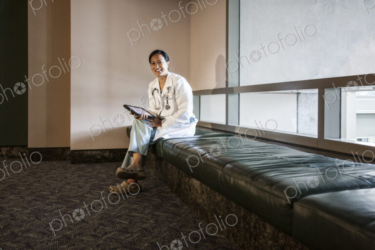 Asian woman doctor using a notebook computer and wearing a lab coat and stethescope.