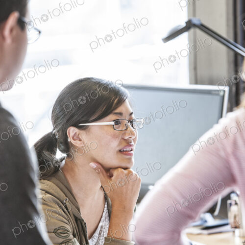 Asian woman leading an informal meeting in a creative office. Asian woman leading an informal meeting in a creative office.