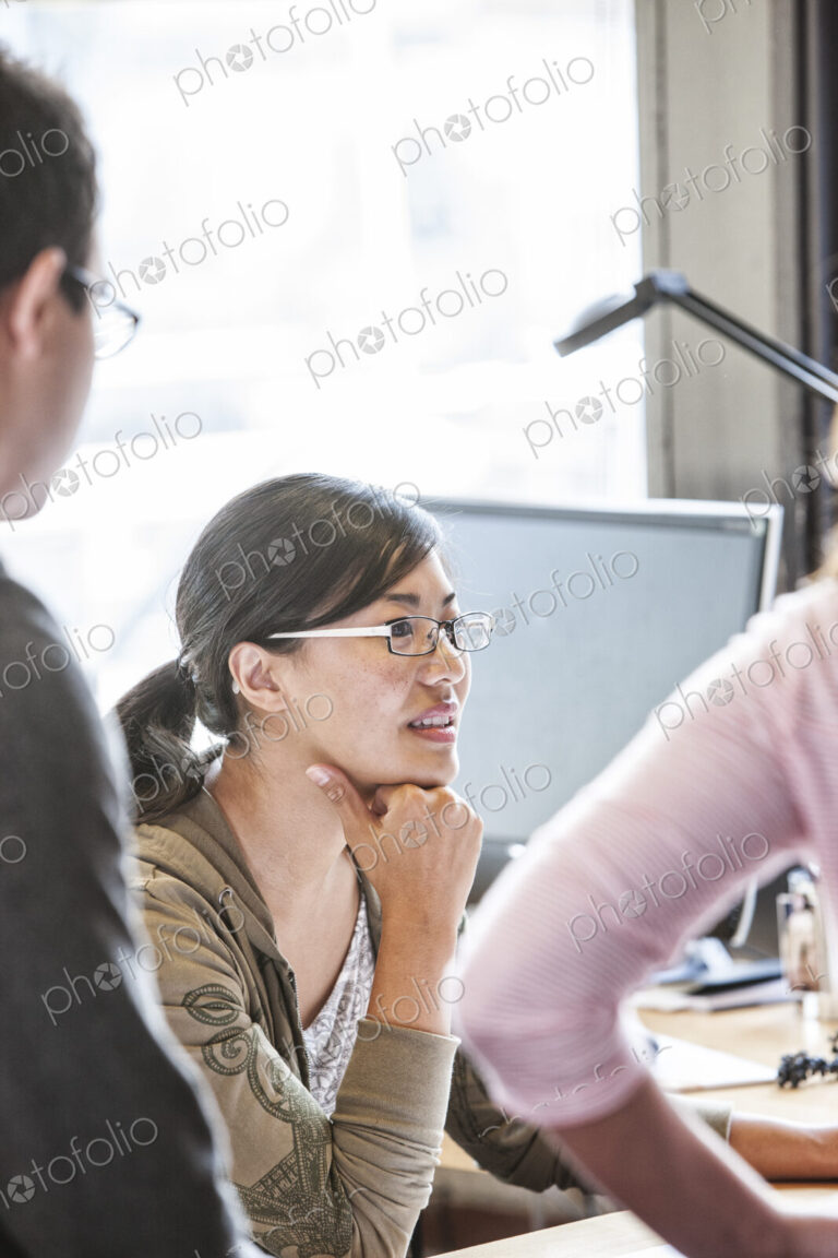 Asian woman leading an informal meeting in a creative office.