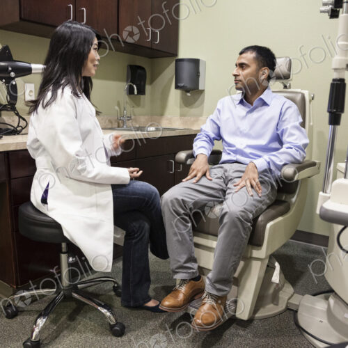 Asian woman ophthalmologist working with an east Indian male patient in an examination… Asian woman ophthalmologist working with an east Indian male patient in an examination…
