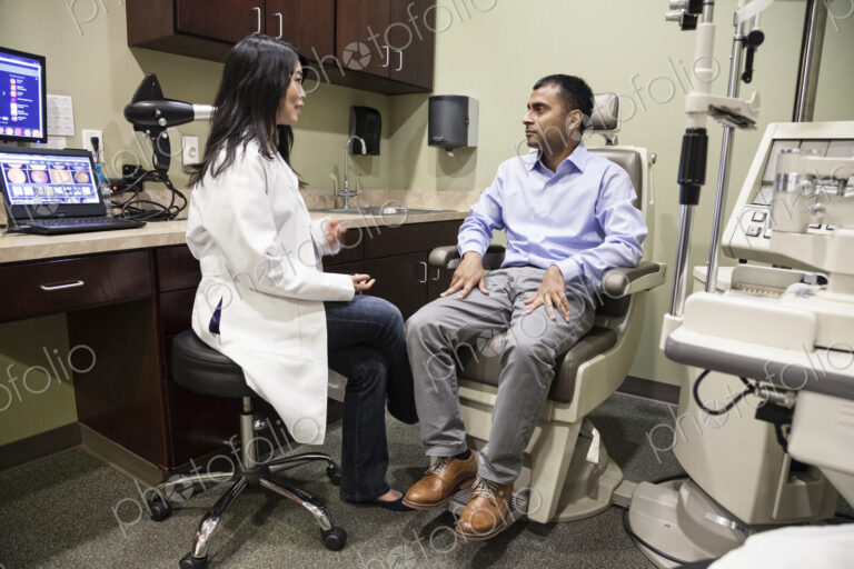 Asian woman ophthalmologist working with an east Indian male patient in an examination…