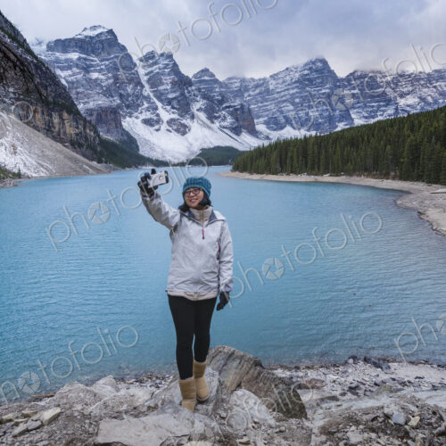 Asian woman posing for cell phone selfie at mountain lake Asian woman posing for cell phone selfie at mountain lake