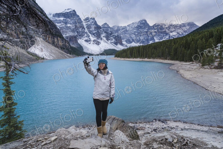 Asian woman posing for cell phone selfie at mountain lake