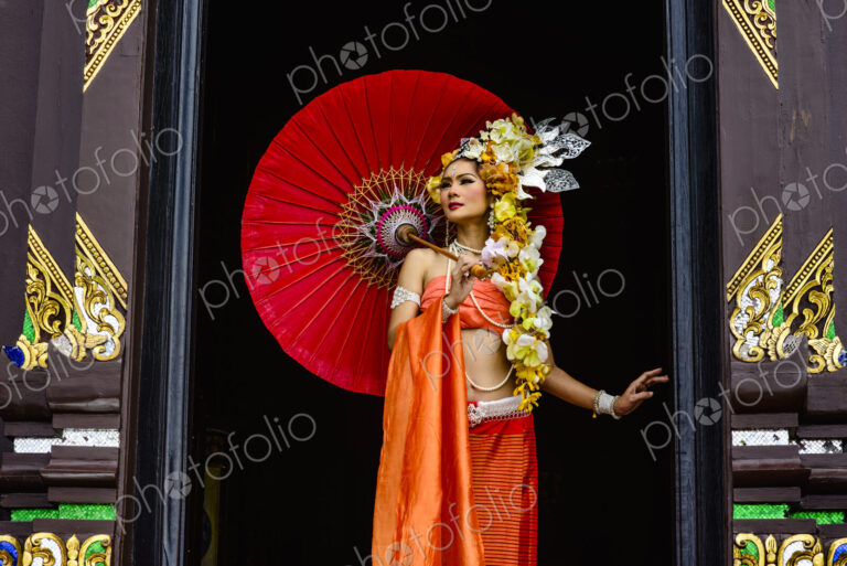 Asian woman standing in ornate temple doorway, Chiang Mai, Chiang Mai, Thailand