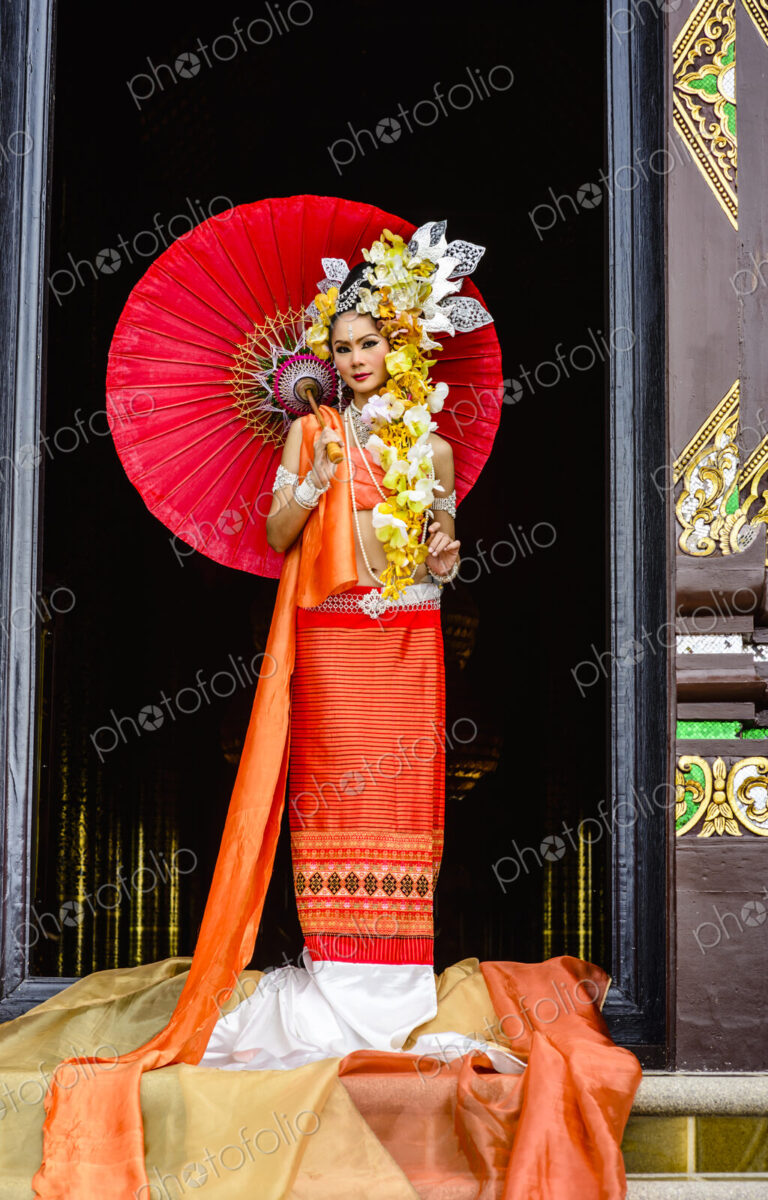 Asian woman standing in ornate temple doorway, Chiang Mai, Chiang Mai, Thailand