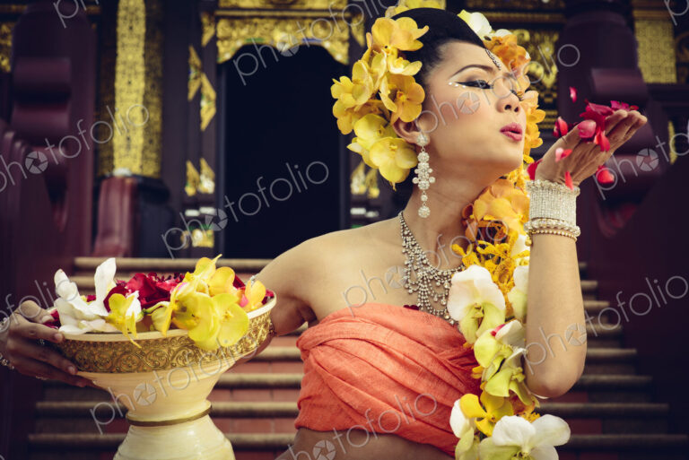 Asian woman with petals on stairs of ornate Buddhist temple, Chiang Mai, Chiang Mai,…