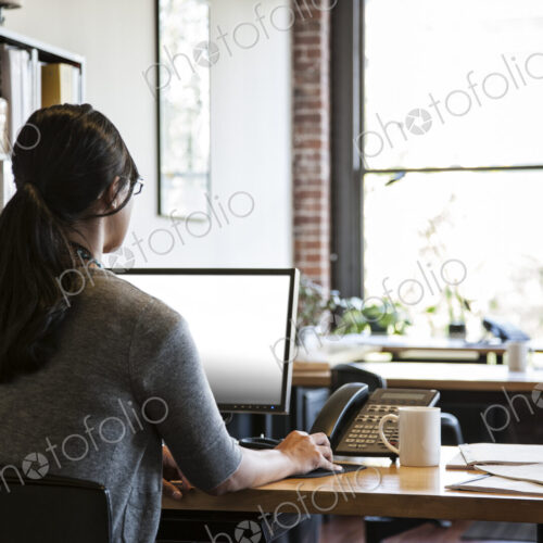 Asian woman working at her desk in a creative office.
