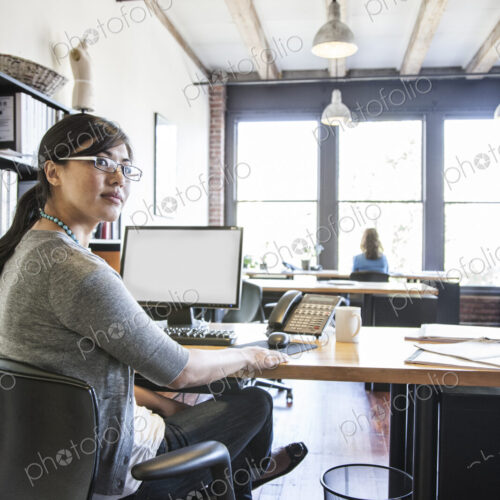 Asian woman working at her desk in a creative office.