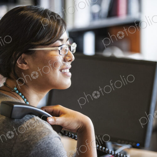 Asian woman working at her desk in a creative office. Asian woman working at her desk in a creative office.