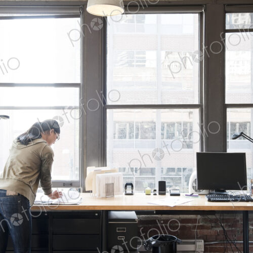 Asian woman working at her office workstation in a creative office.